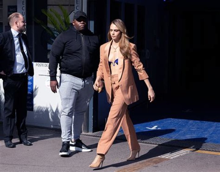 Cara Delevingne Rocks Tiny Blue Crop Top Under A Tan Suit At ‘Planet Sex’ Press Conference