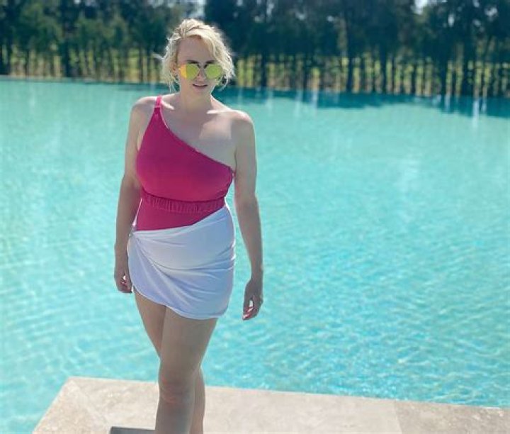 Rebel Wilson Stuns In Pink One-Piece Swimsuit On The Beach: ‘Let’s Get Physical’
